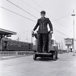 841575 Afbeelding van een stationsassistent op een elektrokar voor bagagevervoer op een perron van het N.S.-station ...